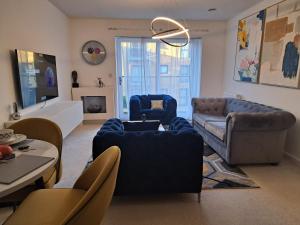 ein Wohnzimmer mit blauen Sofas und einem Tisch in der Unterkunft Stunning Station Apartment in Kent