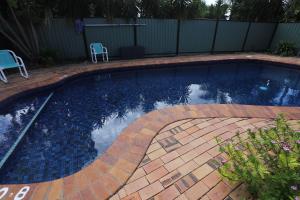 a swimming pool in a yard with two chairs in it at Great Eastern Motor Inn Gympie in Gympie