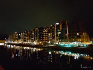 a city lit up at night next to the water at SKIPPER ROOMS Gdańsk in Gdańsk