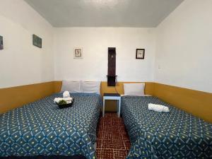 une chambre avec deux lits et une table dans l'établissement Casa del viajero Antigua, à Antigua Guatemala
