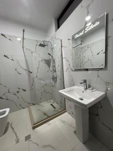 a white bathroom with a sink and a mirror at Hotel Silvio in Fier