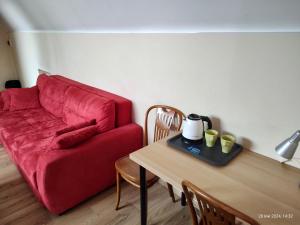 グダニスクにあるSKIPPER ROOMS Gdańskのリビングルーム(赤いソファ、テーブル付)