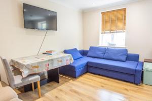 uma sala de estar com um sofá azul e uma mesa em Evergreen Apartments, Flat 3, London em Londres