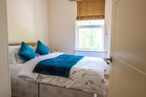 um quarto com uma cama com almofadas azuis e uma janela em Evergreen Apartments, Flat 3, London em Londres