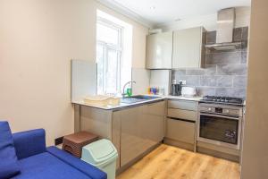a kitchen with a blue couch and a blue chair at Evergreen Apartments, Flat 3, London in London
