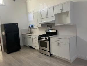 舊金山的住宿－Quesada Homestay，厨房配有白色橱柜和黑色冰箱。