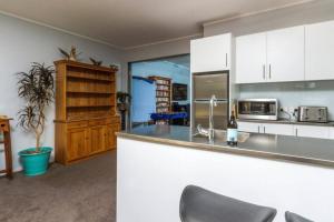 a kitchen with white cabinets and a counter top at Beachside Bliss Castor Bay - Holiday by the Beach in Auckland