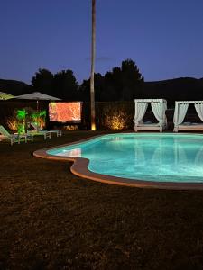 uma piscina à noite com cadeiras e um ecrã em Villa Cas Hespero em San Antonio