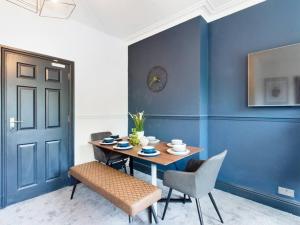 une salle à manger avec des murs bleus, une table et des chaises dans l'établissement Modern Maisonette ideal for larger groups, contractors and professionals, à Liverpool