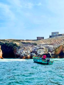 HOSPEDAJE WELCOME paracas في باراكاس: قارب في الماء بجانب شاطئ صخري