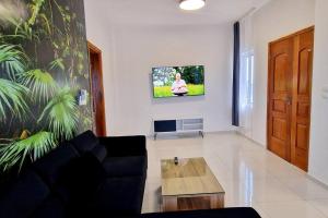 sala de estar con sofá y TV en la pared en Jungle Sensation, en Lomé