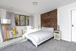 1 dormitorio con cama blanca y pared de ladrillo en 5 o'clock Somewhere en Masterton