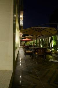 a patio with tables and chairs and umbrellas at night at The Loft Grande in Lahore