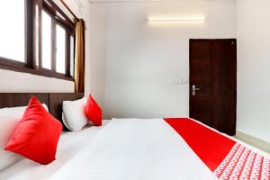 Flagship Agniv Residency في نيودلهي: غرفة نوم بسرير ومخدات حمراء وباب