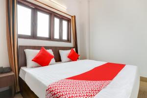Flagship Agniv Residency في نيودلهي: غرفة نوم بسرير ومخدات حمراء وبيضاء
