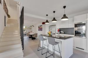 una cucina con pareti bianche e un'isola con sgabelli da bar di Family friendly apartments with a swimming pool Podgora, Makarska - 11937 a Podgora