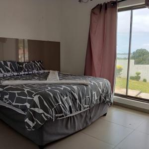 a bed with a black and white comforter and a window at Luxury 2-story retreat with private pool in Bilene beach in Macia