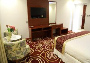 Habitación de hotel con cama, escritorio y TV. en Wow Hotel Jeddah en Yeda