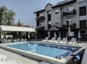 uma piscina com cadeiras e guarda-sóis ao lado de um edifício em Apartments Milsa Lux em Sokobanja