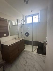 een badkamer met een wastafel en een glazen douche bij Le cyprès avec jacuzzi seh'loué in Ploufragan