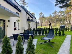 een patio met stoelen en bomen in een tuin bij La Brisa Apartments in Dziwnówek