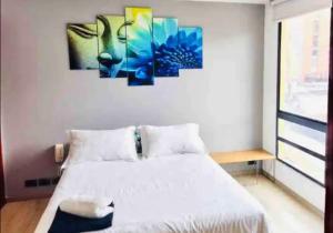 a bedroom with a bed with three paintings on the wall at Ultimate Whole Floor Apartment in Bogotá