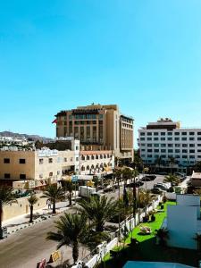 een stad met gebouwen en een straat met palmbomen bij Pizza Street Hostel in Aqaba