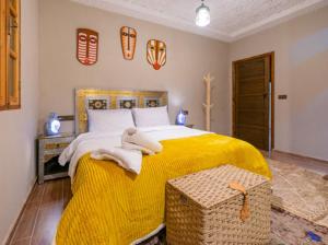 - une chambre avec un grand lit et une couverture jaune dans l'établissement Riad Atlas Dreams Imlil, à Imlil