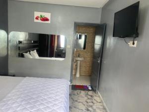 a bedroom with a bed and a bathroom with a mirror at Sunrise Center Bonapriso 111 in Douala