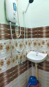 La salle de bains est pourvue d'un lavabo et d'un sèche-cheveux sur le mur. dans l'établissement WK HOMESTAY PASIR MAS, à Pasir Mas