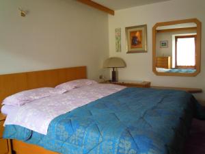 una camera da letto con un letto con un piumone blu e uno specchio di Luigi Apartment a Varena