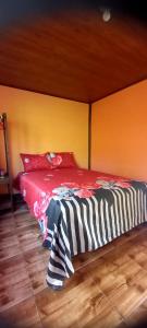 Ce lit se trouve dans une chambre dotée d'un mur rouge et jaune. dans l'établissement Cabañas Zunzun, à San Ramón