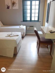 a hotel room with two beds and a desk and a window at Hotel Internacional São Paulo in Sao Paulo