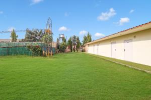 Palette - JPS Residency في جورجاون: ساحة عشبية كبيرة مع مبنى وملعب