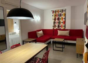 uma sala de estar com um sofá vermelho e uma mesa em Aparthotel Boutique Poniente Playa em San Antonio