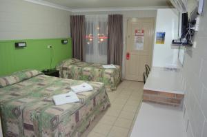 a hotel room with two beds and a television at Welcome Home Motel Rockhampton in Rockhampton