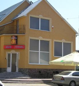 a yellow house with a car parked in front of it at Hotel Vatra in Lviv