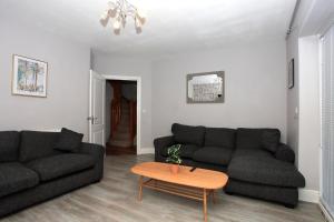 uma sala de estar com dois sofás pretos e uma mesa em Spacious & Relaxing Gem - Hot Tub - Games - Parking! em Peterborough