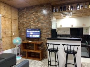 a kitchen with two bar stools and a television at Altheos Place Romblon Cottage 1 in Romblon