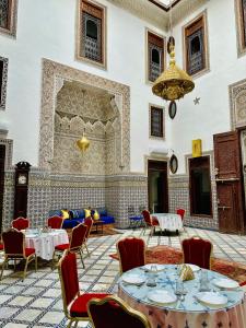 Habitación grande con mesas, sillas y lámpara de araña. en Riad Dilar Fes & Spa en Fez