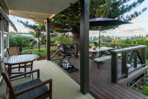 a wooden deck with a table and an umbrella at Cascade Garden Apartments in Burnt Pine
