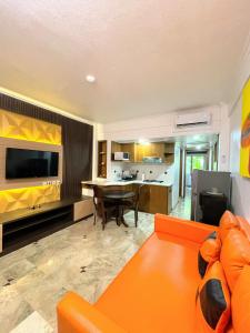 a living room with an orange couch and a kitchen at Suite Hotel Apartment Legian by RCP in Seminyak
