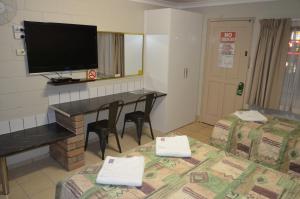 a hotel room with two beds and a television at Welcome Home Motel Rockhampton in Rockhampton