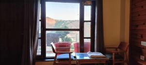ein Fenster mit Stühlen und einem Tisch davor in der Unterkunft The Tranquil hotel in Chakrata