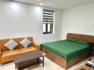 a bedroom with a bed and a couch and a window at HPT Apartment chuỗi căn hộ Hoàng Huy Riverside HP in Abbeyfeale
