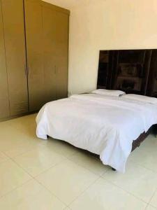 1 dormitorio con 1 cama grande con sábanas blancas en 2nd street home, en Lusaka