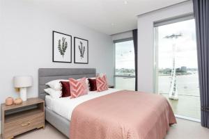 Un dormitorio con una cama con almohadas rosas y una ventana en Greenwich- The O2 en Londres