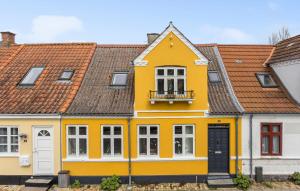Casa amarilla con ventanas blancas y balcón. en Stunning Home In Rudkbing With Kitchen, en Rudkøbing