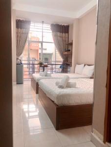 two beds in a room with a large window at Thanhha Guesthouse in Ho Chi Minh City