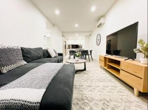 een woonkamer met een bank en een flatscreen-tv bij Mega Style Apartments Kings Domain in Melbourne